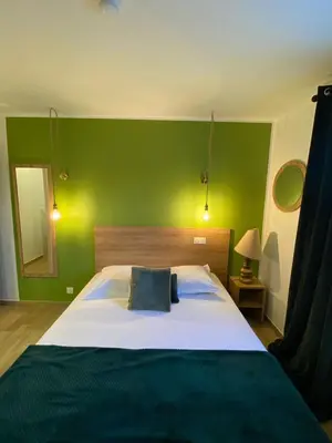 a bedroom with a large bed with a green wall at Hotel U Catagnu in San-Nicolao