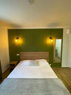 a bedroom with a large bed with a green wall at Hotel U Catagnu in San-Nicolao