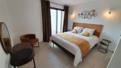 a bedroom with a bed and a table and a chair at Villa Nananthée T5 de luxe,4-8 pers, piscine privée chauffée in Lecci