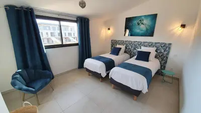 a bedroom with two beds and a chair and a window at Villa Nananthée T5 de luxe,4-8 pers, piscine privée chauffée in Lecci
