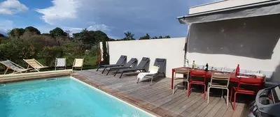 a patio with a table and chairs next to a pool at Villa Nananthée T5 de luxe,4-8 pers, piscine privée chauffée in Lecci