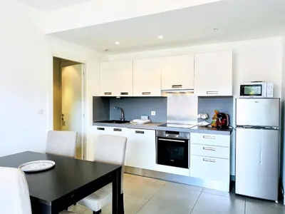 a kitchen with a black table and a white refrigerator at Jardins de Quatrina centre ville in Propriano