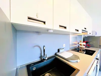 a kitchen with white cabinets and a sink at Jardins de Quatrina centre ville in Propriano
