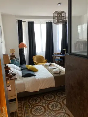 a bedroom with a bed with pillows and a chair at Hôtel La Demeure Coloniale in Moriani Plage