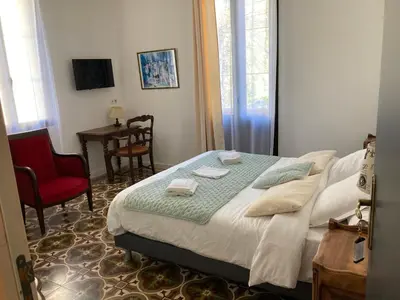 a bedroom with a bed and a red chair at Hôtel La Demeure Coloniale in Moriani Plage