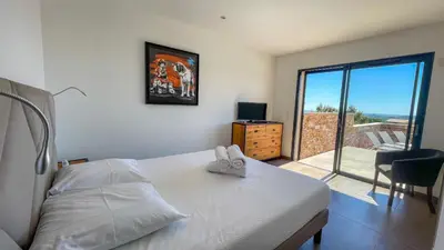 a bedroom with a bed and a view of a balcony at Tres belle villa neuve vue mer avec piscine chauffee in Sainte-Lucie de Porto-Vecchio