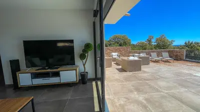 a living room with a television and a patio at Tres belle villa neuve vue mer avec piscine chauffee in Sainte-Lucie de Porto-Vecchio