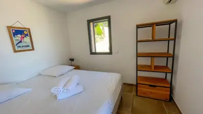 a bedroom with a white bed and a book shelf at Tres belle villa neuve vue mer avec piscine chauffee in Sainte-Lucie de Porto-Vecchio
