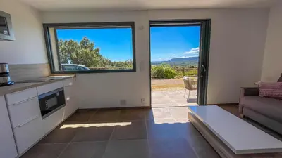 a kitchen with a view of a living room at Tres belle villa neuve vue mer avec piscine chauffee in Sainte-Lucie de Porto-Vecchio