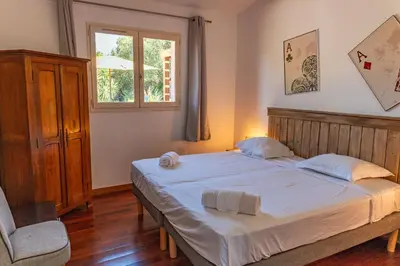 a bedroom with a bed and a chair and a window at Villa Calyaunati Di San Ciprianu in Lecci