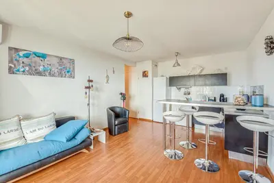 a living room with a blue couch and a kitchen at Cappella in Ajaccio