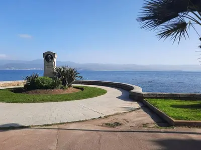 a walkway next to the ocean with a clock tower at studio cappella in Ajaccio
