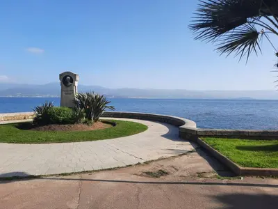 a walkway next to the ocean with a clock tower at studio cappella in Ajaccio