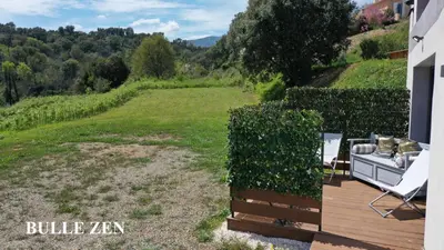 a deck with a chair and a hedge at Corse et Zen BULLE ZEN 25 m² 2 pers + Bébé in Folelli