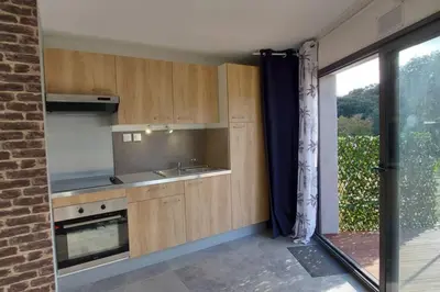 a kitchen with wooden cabinets and a large window at Corse et Zen BULLE ZEN 25 m² 2 pers + Bébé in Folelli