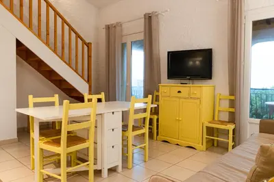 a living room with a yellow table and a tv at Résidence Marie Diane - Laurier des Mers in Propriano