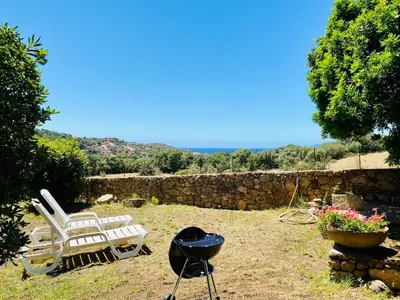 a bbq and two chairs and a grill in a yard at Résidence Marie Diane - Laurier des Bois in Propriano