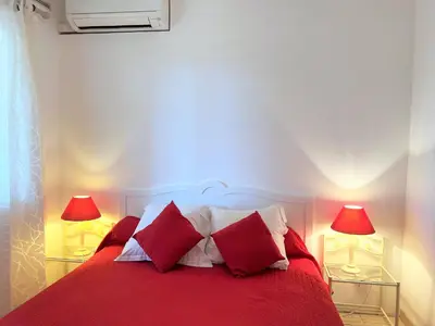 a bedroom with a red bed with two lamps at Résidence Marie Diane - Laurier des Bois in Propriano