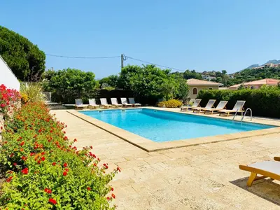 a swimming pool with lounge chairs and flowers at Résidence Marie Diane - Laurier des Bois in Propriano