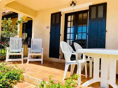 a patio with white chairs and a table and blue doors at Résidence Marie Diane - Duplex Vue Piscine A in Propriano