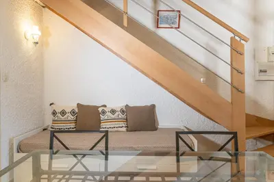 a living room with a bed under the stairs at Résidence Marie Diane - Duplex Coté Mer C in Propriano