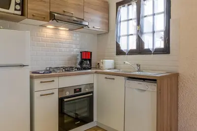 a kitchen with white cabinets and a stove and a sink at Résidence Marie Diane - Duplex Coté Mer C in Propriano