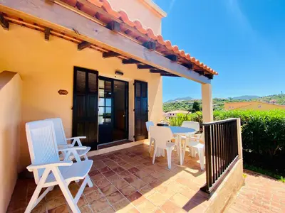 a patio with white chairs and a table with a view at Résidence Marie Diane - Duplex Coté Mer C in Propriano