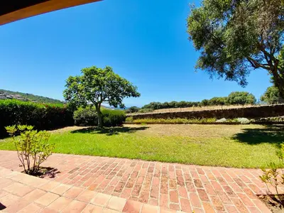 a brick walkway with a field of grass and a tree at Résidence Marie Diane - Duplex Coté Mer D in Propriano