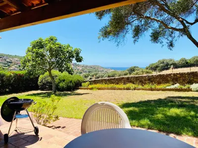 a patio with a grill and a table and chairs at Résidence Marie Diane - Duplex Coté Mer E in Propriano