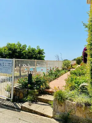 a white fence next to a garden with flowers at Résidence Marie Diane - Appart vue mer et piscine G in Propriano