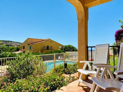 a group of chairs sitting on a patio with a pool at Résidence Marie Diane - Appart vue mer et piscine G in Propriano
