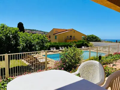 a table and chairs in front of a fence with a pool at Résidence Marie Diane - Appart vue mer et piscine G in Propriano