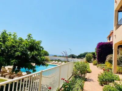 a view of a pool from a house with a fence and flowers at Résidence Marie Diane - Appart vue mer et piscine G in Propriano
