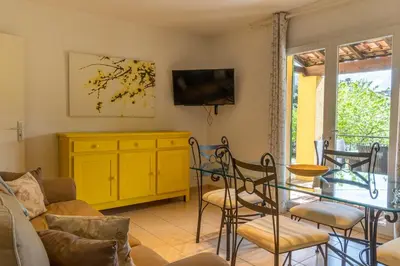 a living room with a glass table and a yellow cabinet at Résidence Marie Diane - Laurier Rose in Propriano