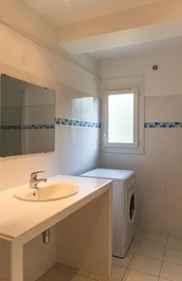a bathroom with a sink and a washing machine at Résidence Marie Diane - Laurier Rose in Propriano