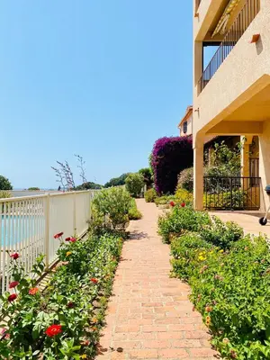 a brick walkway next to a building with flowers at Duplex vue Piscine B in Propriano