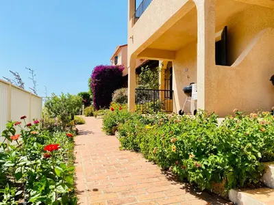 a brick walkway in front of a building with flowers at Duplex vue Piscine B in Propriano