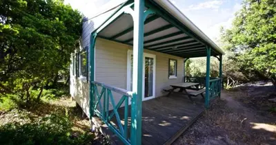 a small house with a picnic table on a porch at Location de chalet Meremaki in Pianottoli-Caldarello