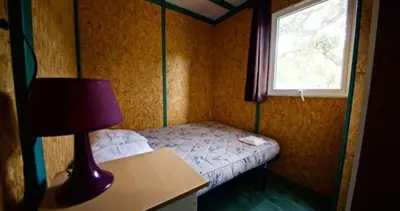 a small bedroom with a bed and a window at Location de chalet Meremaki in Pianottoli-Caldarello