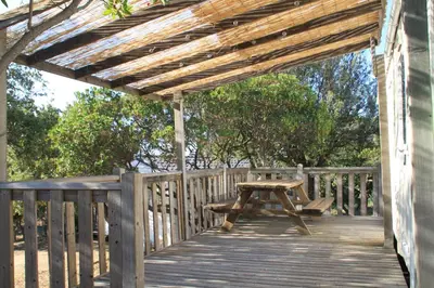 a wooden deck with a picnic table and a wooden pergola at Location de chalet Meremaki in Pianottoli-Caldarello