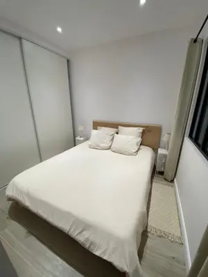 a bedroom with a white bed with white sheets and pillows at Ajaccio Magnifique T2 45m2 neuf 5 personnes Clim wifi stationnement gratuit centre ville plage à 300m in Ajaccio