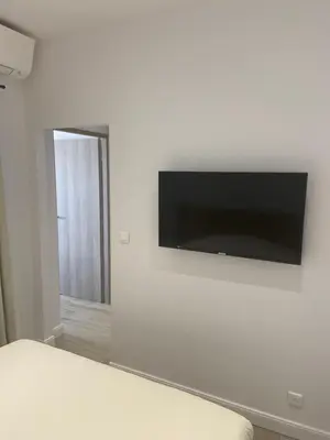 a flat screen tv hanging on a white wall at Ajaccio Magnifique T2 45m2 neuf 5 personnes Clim wifi stationnement gratuit centre ville plage à 300m in Ajaccio