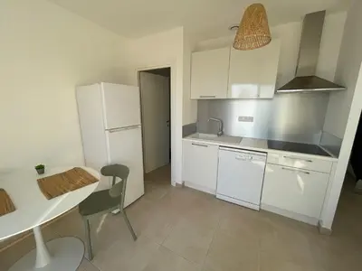 a kitchen with white cabinets and a table and a chair at Résidence Marina Di Bravone in Linguizzetta