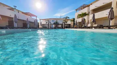 a swimming pool with blue water in front of buildings at Résidence Marina Di Bravone in Linguizzetta