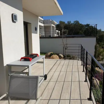 a deck with a table and a red object on it at Villa Le Figuier 6 pers piscine chauffée 2 min plage en voiture in Sainte-Lucie de Porto-Vecchio