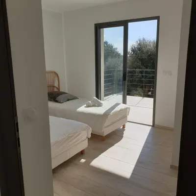 a room with two beds and a large window at Villa Le Figuier 6 pers piscine chauffée 2 min plage en voiture in Sainte-Lucie de Porto-Vecchio
