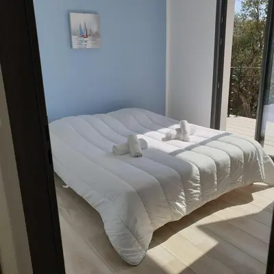 a large white bed in a room with a window at Villa L'Arbousier 4 pers piscine chauffée 2 min plage en voiture in Sainte-Lucie de Porto-Vecchio