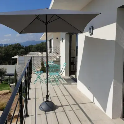 a patio with an umbrella on a balcony at Villa L'Arbousier 4 pers piscine chauffée 2 min plage en voiture in Sainte-Lucie de Porto-Vecchio