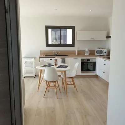 a kitchen with a table and chairs in a room at Villa L'Arbousier 4 pers piscine chauffée 2 min plage en voiture in Sainte-Lucie de Porto-Vecchio