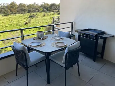 a table with two chairs and a stove on a balcony at CASA STANATURA in Porto-Vecchio